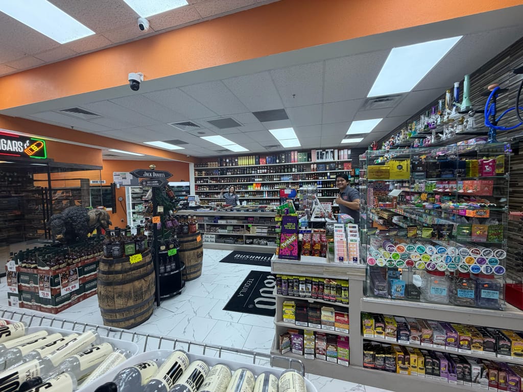 Inside Liquor Cave: aisles of spirits, bourbon barrels, a cigar sign and the smoke-shop counter