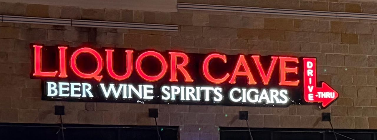 Close-up of the neon sign: Liquor Cave, beer, wine, spirits, cigars, drive-thru